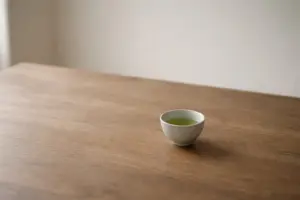 Chén chè xanh đặt một mình trên bàn gỗ trong ánh sáng tự nhiên.