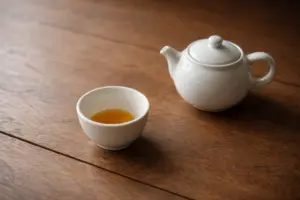 Chén trà gần cạn và ấm trà nhỏ đặt yên trên bàn gỗ trong ánh sáng tự nhiên