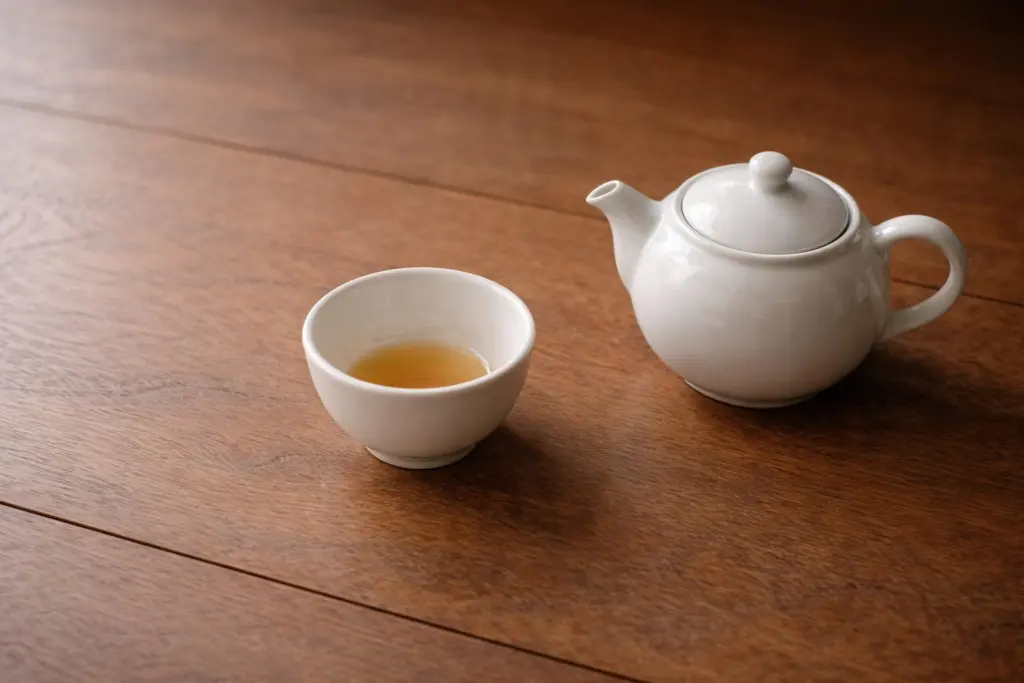 Ấm trà nhỏ và chén trà đã uống xong trên bàn gỗ trong ánh sáng buổi chiều