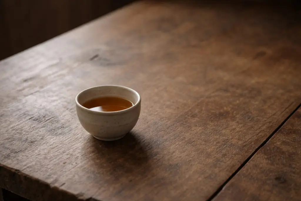 Chén trà đơn độc trên bàn gỗ trong ánh sáng buổi chiều nhẹ