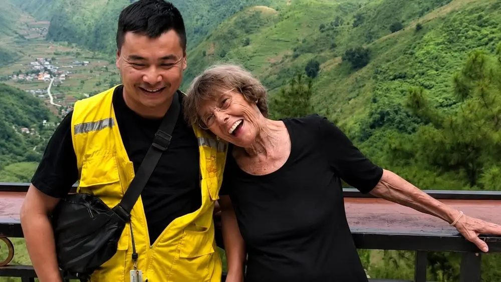 Bà Annemarie cùng tài xế lưu giữ khoảnh khắc đáng nhớ trong chuyến đi khám phá Hà Giang với khung cảnh núi non hùng vĩ.